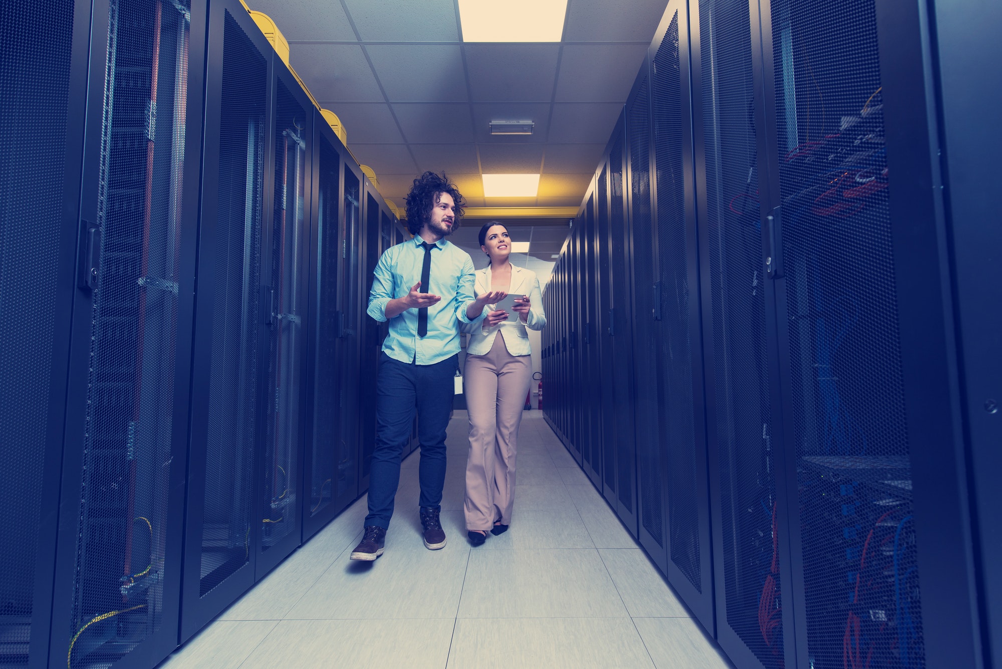 engineer showing working data center server room to female chief