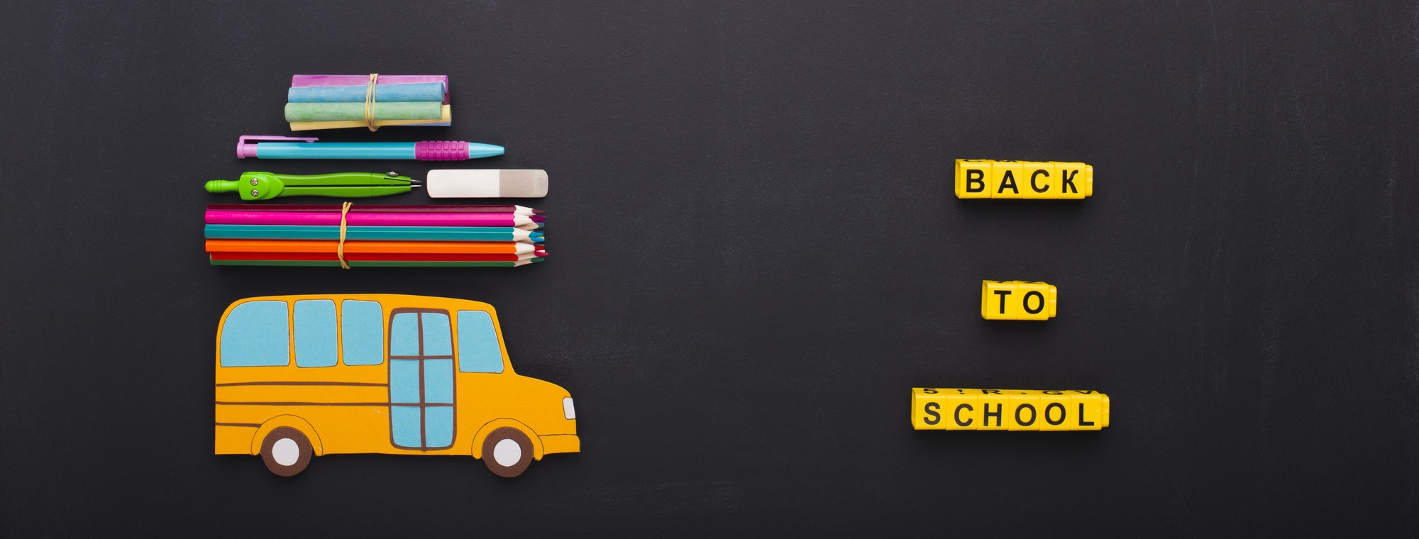 Yellow bus with stationery on chalk board background